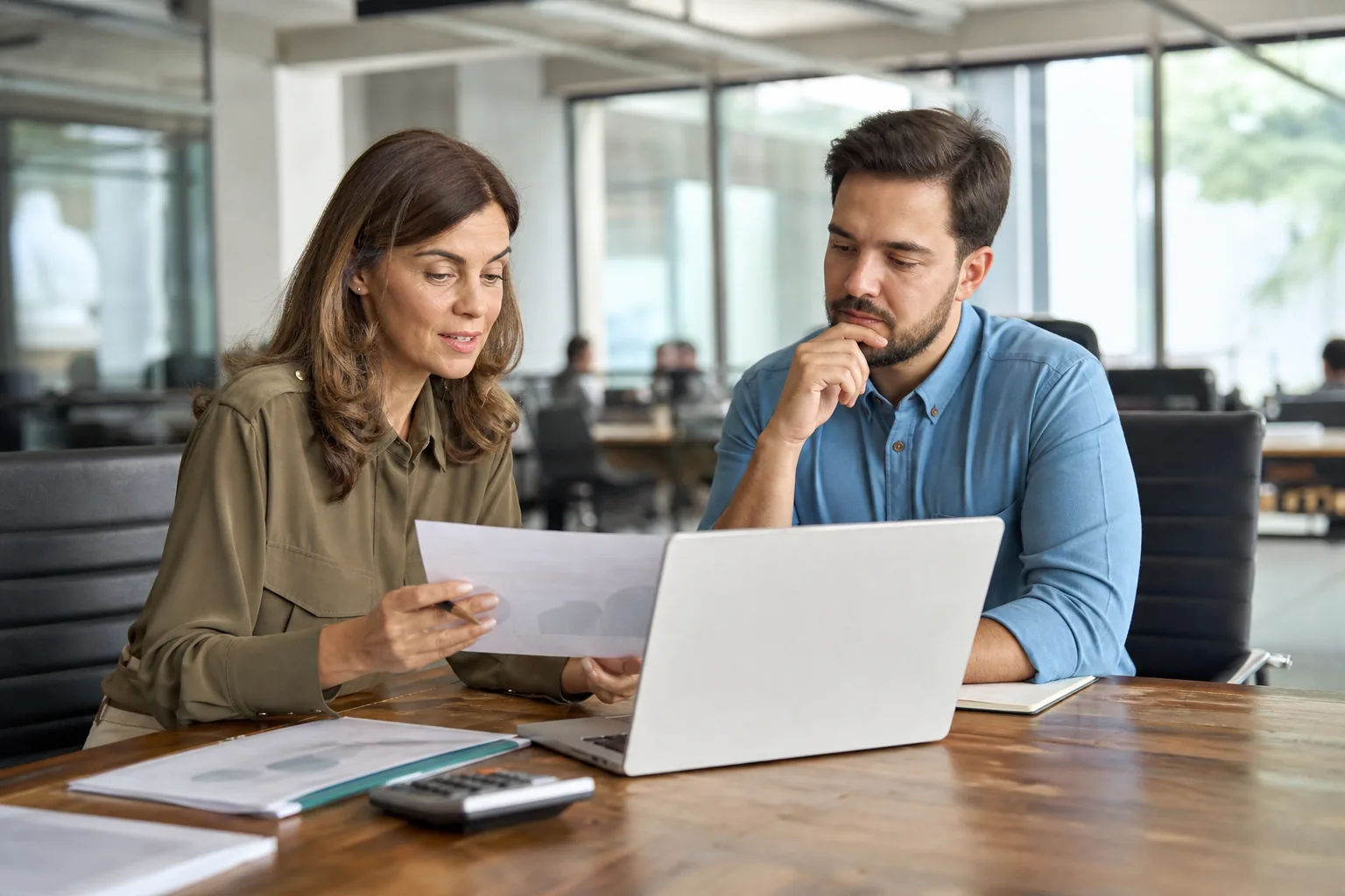 Controller and operations manager comparing procurement software quotes at a conference table